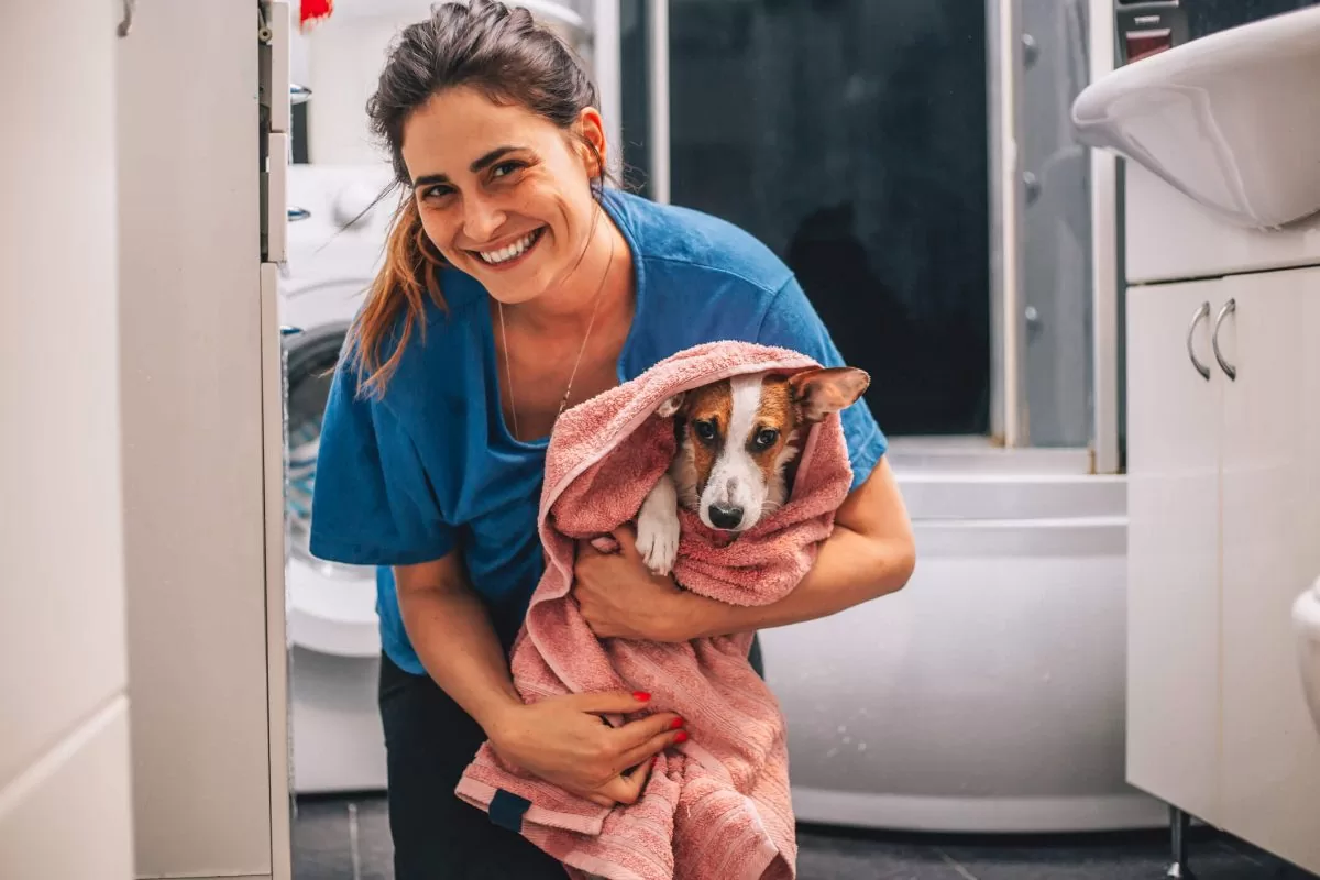 Profissional de banho e tosa segurando cachorro enrolado em toalha – Focinho Feliz Pet Shop, Bauru